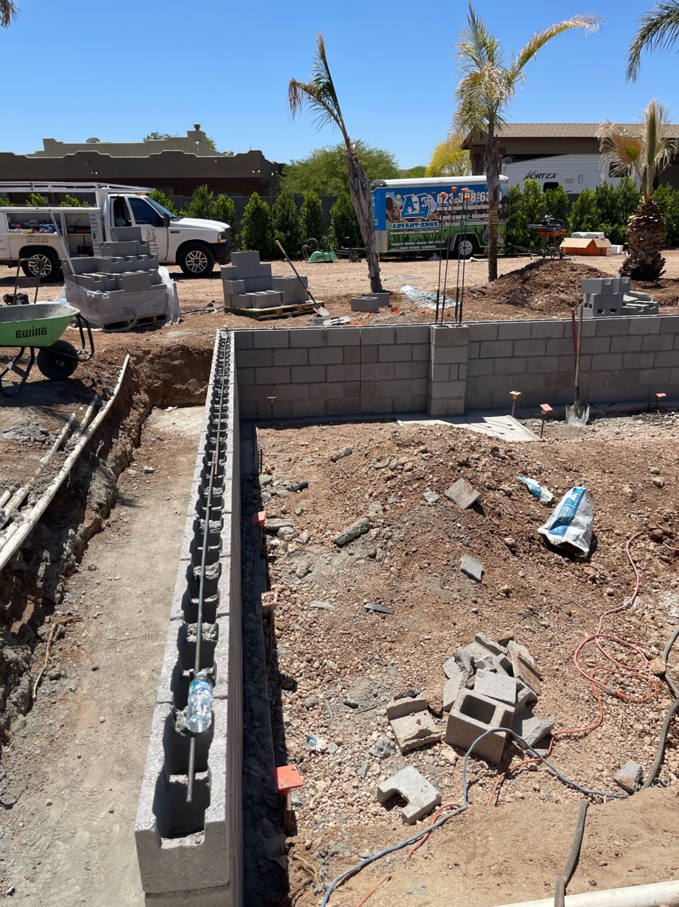 Aurora Estate — long footing trench and wall axis with fresh block work, rebar, and trench depth visible before the area is fully backfilled