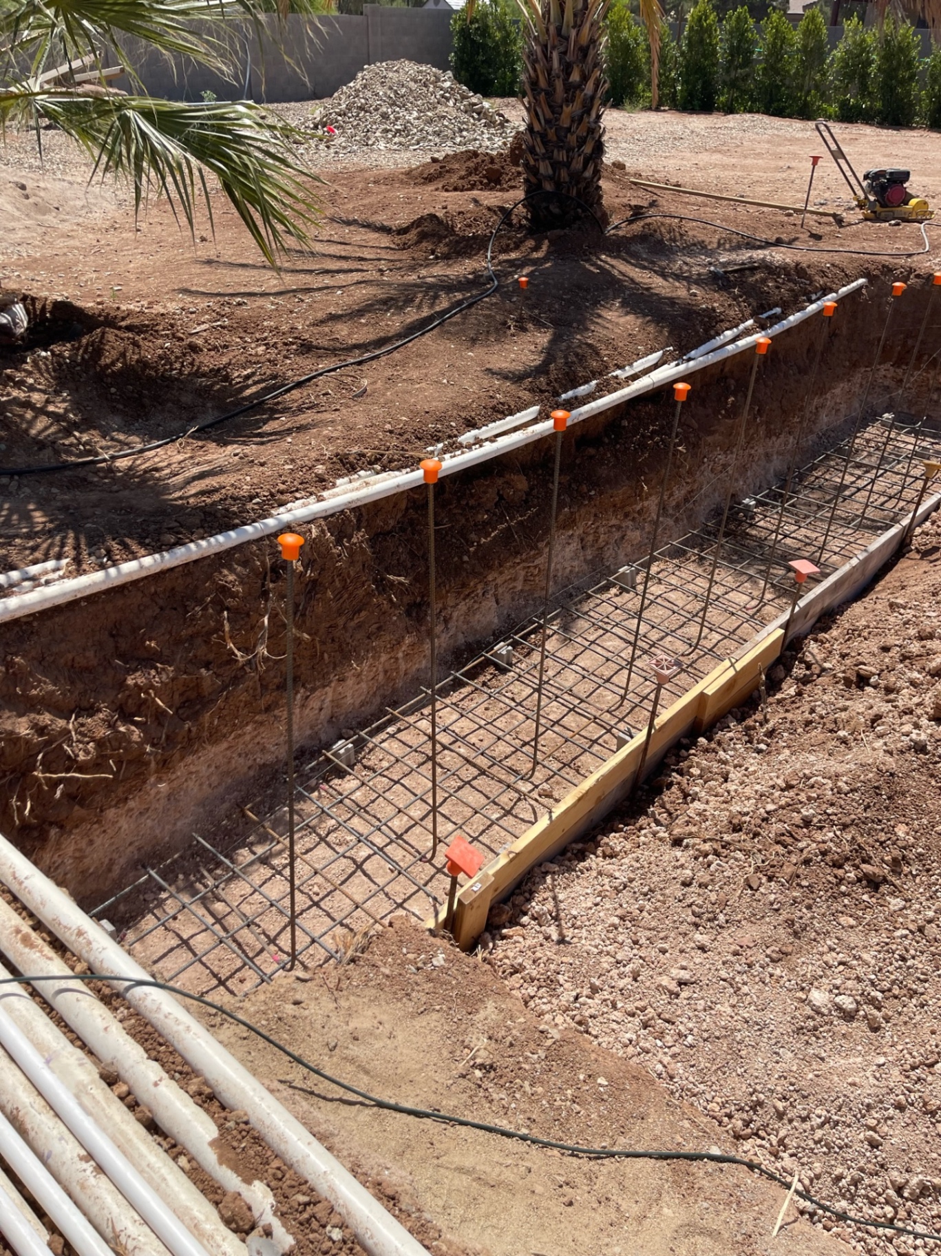 Aurora Estate — long reinforced footing trench with rebar cages set in place for structural walls and hardscape support