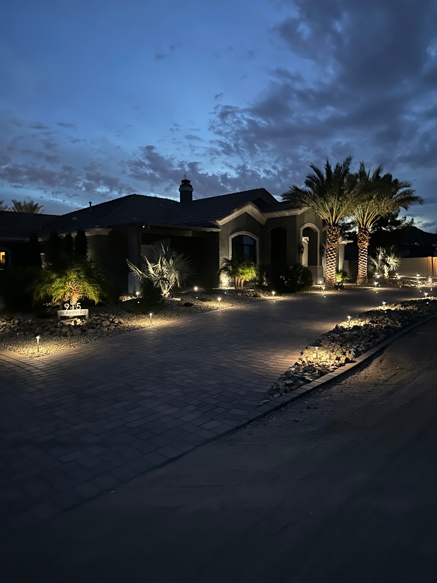 Aurora Estate — full front elevation at twilight with paver drive and path lighting