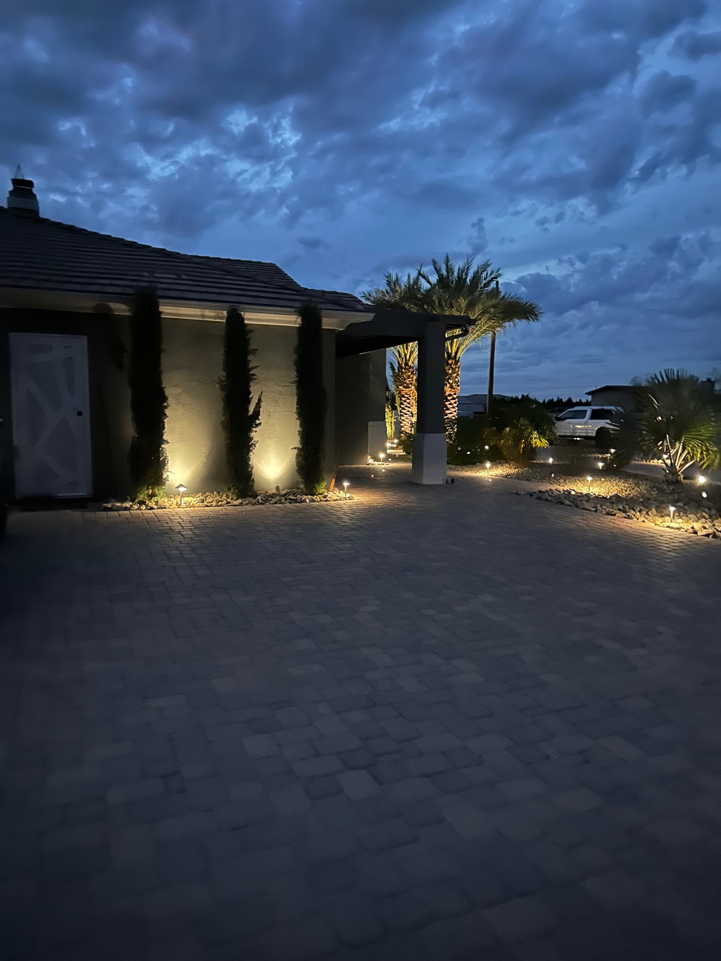 Aurora Estate — side elevation with Italian cypress uplit against stucco