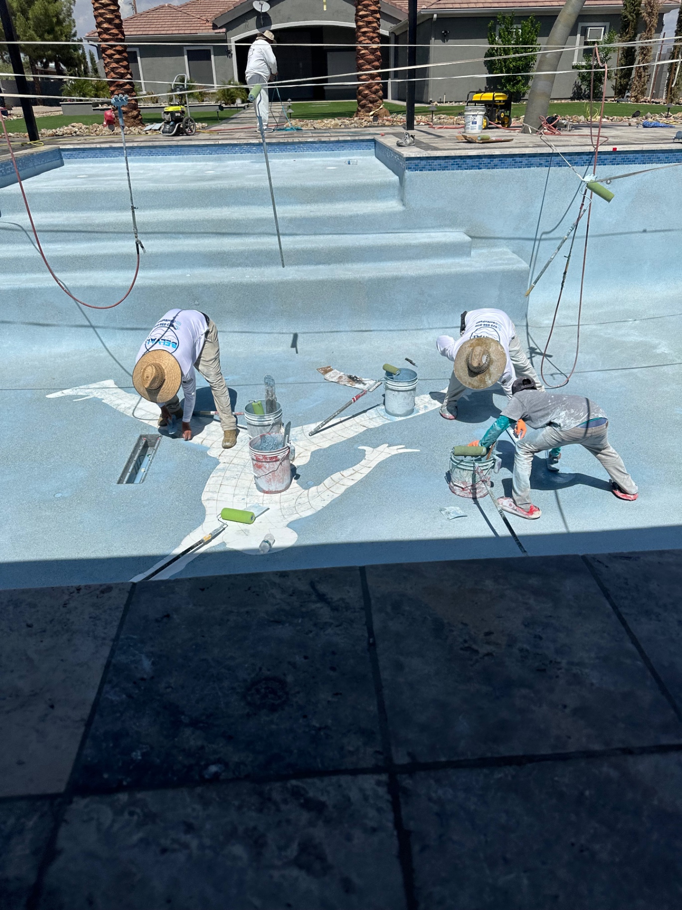 Aurora Estate — installers hand-applying the custom Jumpman silhouette inlay into the pool deck finish