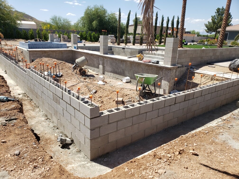 Aurora Estate — perimeter wall corner with vertical rebar set in grouted cells beside the pool excavation