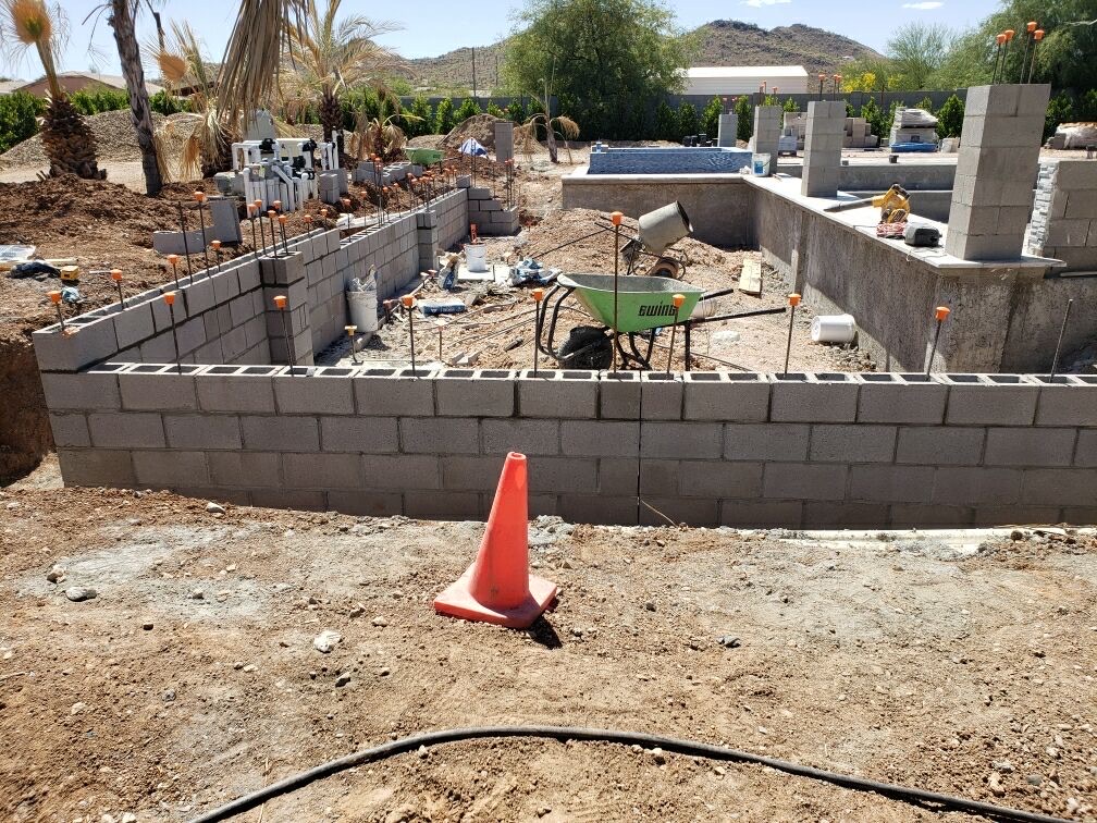 Aurora Estate — finished perimeter block wall with rebar pins set, mountain backdrop, ready for next masonry course