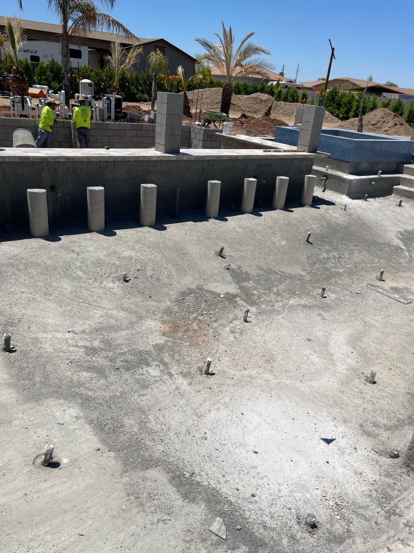 Aurora Estate — inside the pool shell with floor return stub-outs and wall penetrations visible before interior finish, showing the hydraulic layout beneath the final waterline