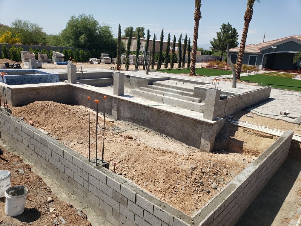 Aurora Estate — alternate angle of the raised spa, planter walls and tiered pool steps mid-build before pebble interior