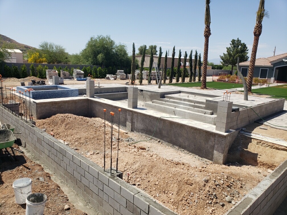 Aurora Estate — wide view of the raised spa, sunken lounge, and pool steps formed in block with travertine treads set