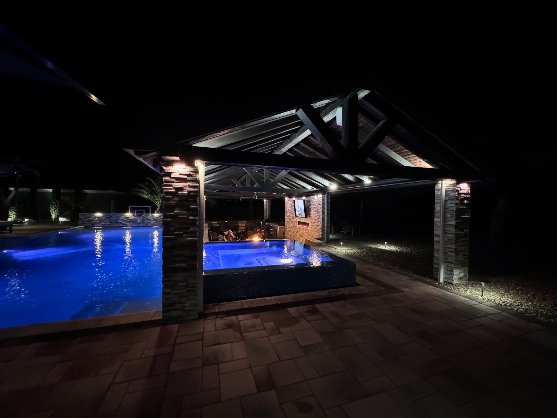 Aurora Estate — gabled ramada with raised spillover spa at twilight