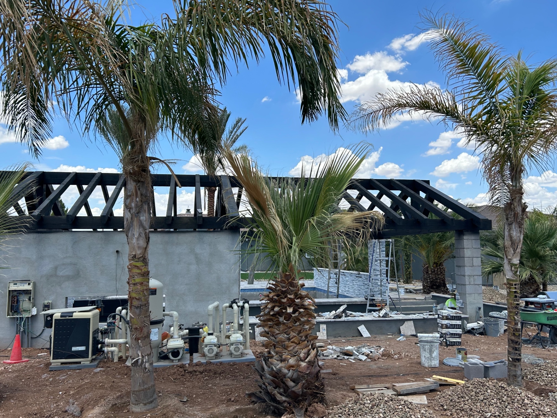 Aurora Estate — mid-build ramada with pool equipment exposed and finish materials staged on site