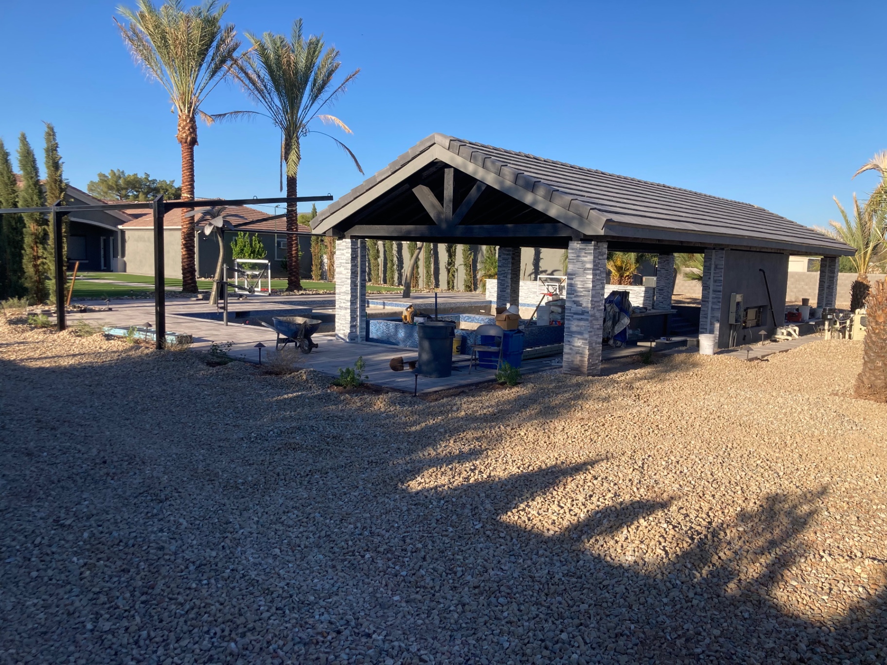 Aurora Estate — near-finish ramada and pool zone with hardscape largely in place before final cleanup
