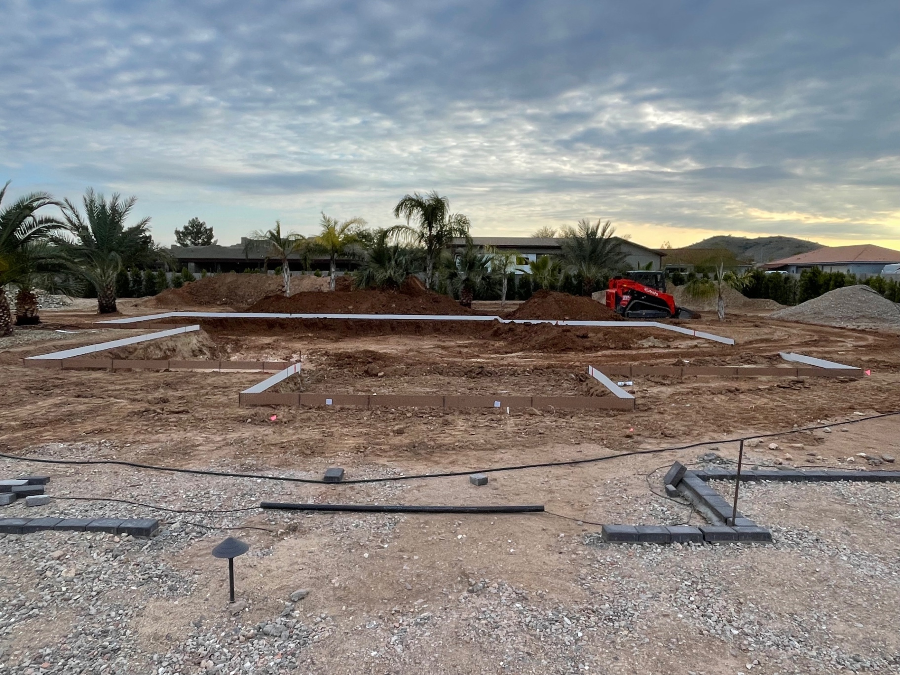 Aurora Estate — early site layout at dusk with the back-yard footprint staked and berms roughed in