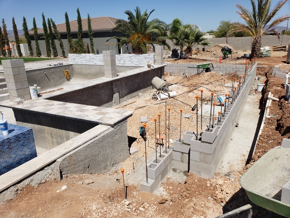 Aurora Estate — raised spa with travertine coping set and rebar columns staged for the planter wall and ramada structure