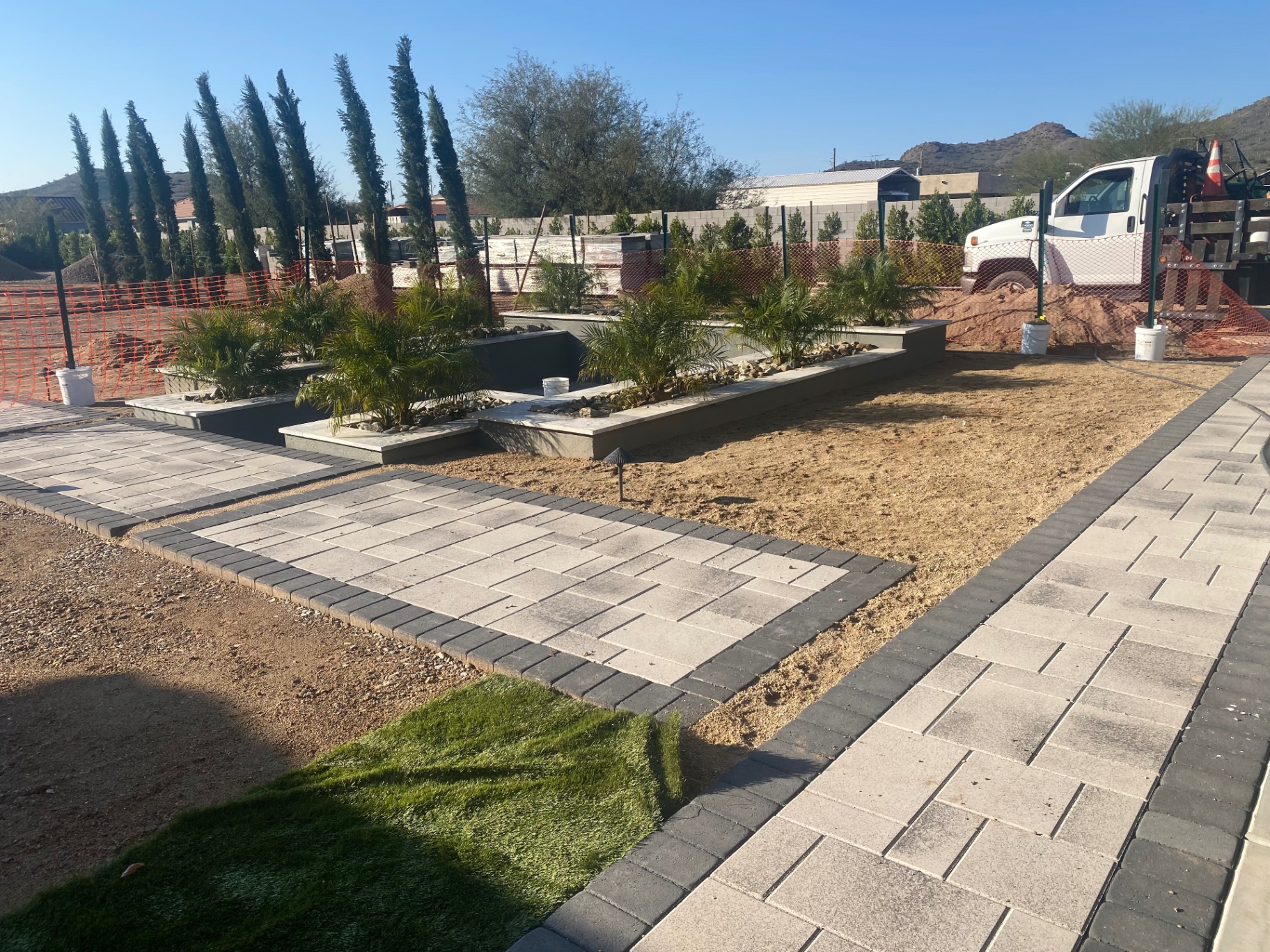 Aurora Estate — spa surround with planters, paver paths, and palms being installed during finish work