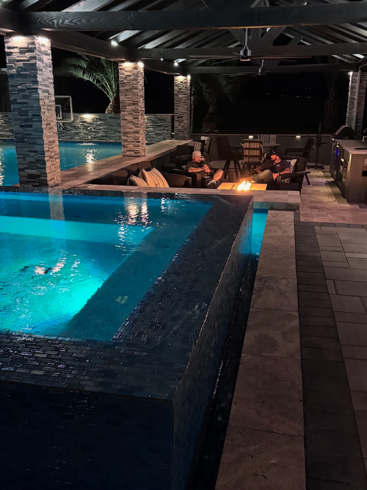Aurora Estate — sunken fire lounge with glass-tile spa wall and outdoor kitchen